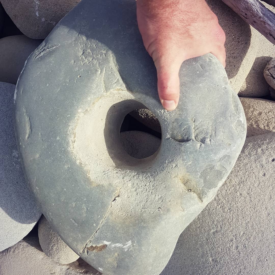 I found another suspicious rock with a hole in it. This one seems to have been worked, the hole is much rougher than the rest of the stone. Swipe for a more modern artifact 😁

Let me know if you think it could have been an weight or anchor!

        